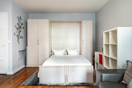 une chambre avec un lit blanc et un canapé dans l'établissement Elegant studio Saint-Dominique, à Paris