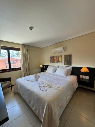a bedroom with a large white bed and a window at Kariri Beach Residence in Caucaia