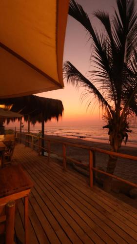 a sunset on the beach with a palm tree at Baja Canoas Hotel in Canoas De Punta Sal
