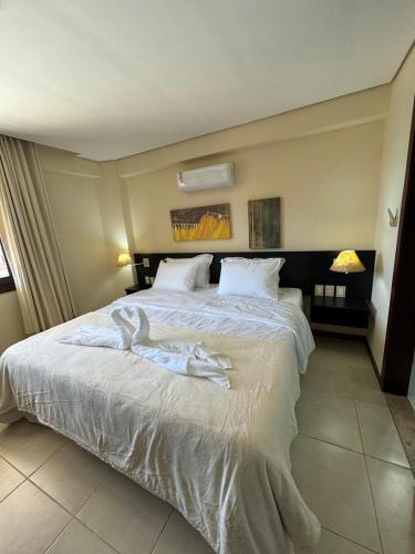 a bedroom with a large bed with white sheets at Kariri Beach Residence in Caucaia