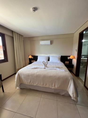 a bedroom with a large white bed with two lamps at Kariri Beach Residence in Caucaia