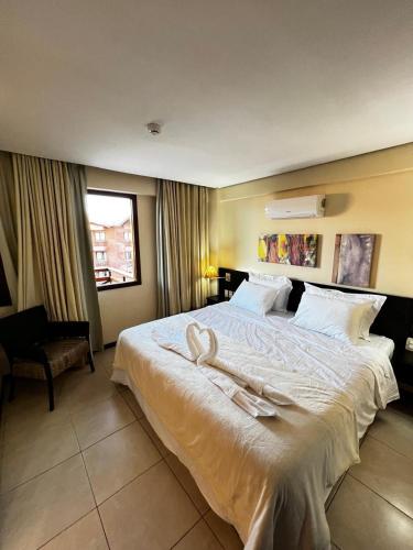 a bedroom with a large bed with white sheets at Kariri Beach Residence in Caucaia