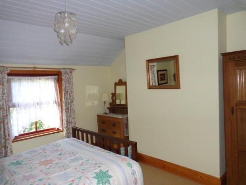 a bedroom with a bed and a window at Ballacowell Cottage in Sulby