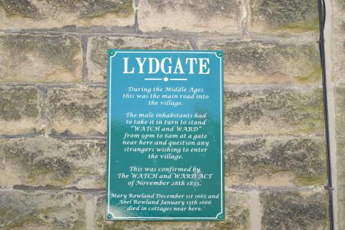 ein Schild an der Seite einer Backsteinmauer in der Unterkunft Traditional 2 Bedroom Cottage in Eyam Hope Valley in Eyam