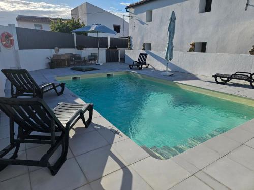 a swimming pool with two chairs and an umbrella at Russa AL in Lentiscais