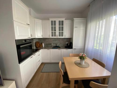 a kitchen with white cabinets and a table with a vase of flowers at Jon Apartment- Perla Resort - Gjiri i Lalzit in Lalzit Bay