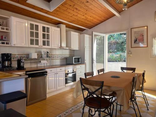 a kitchen with a table and chairs and a kitchen with white cabinets at Maison volets bleus - jusqu'à 9 personnes - 3 chambres - Arcachon Centre in Arcachon