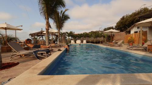 a man laying on a chair next to a swimming pool at Baja Canoas Hotel in Canoas De Punta Sal