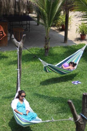 two people laying in hammocks on the grass at Baja Canoas Hotel in Canoas De Punta Sal