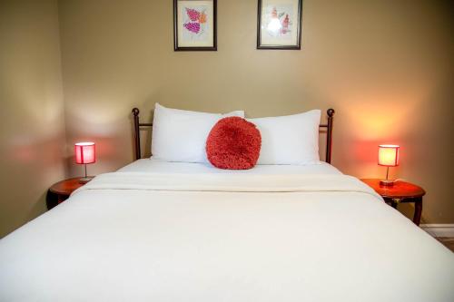 a red pillow sitting on a bed with two lamps at Petals Suite Patio Nature Trails Bancroft in Bancroft