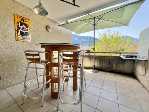 - une cuisine avec une table, des chaises et un parasol dans l'établissement Annecy Genève Rochexpo & Vintage car, à Bonneville