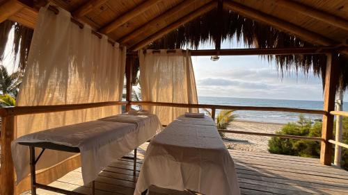 a porch with two beds and a view of the beach at Baja Canoas Hotel in Canoas De Punta Sal