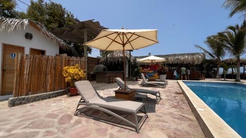 a group of chairs and an umbrella next to a pool at Baja Canoas Hotel in Canoas De Punta Sal