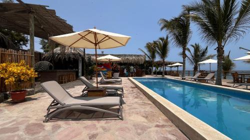 a swimming pool with lounge chairs and an umbrella at Baja Canoas Hotel in Canoas De Punta Sal
