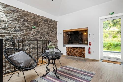 a balcony with a table and chairs and a stone wall at Villa Pomar, By OP in Senhora do Rosário