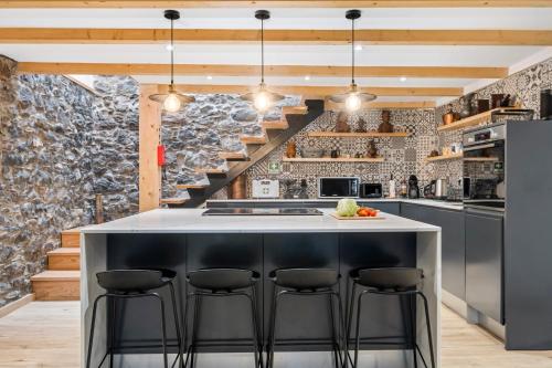 a kitchen with a large island with stools at Villa Pomar, By OP in Senhora do Rosário