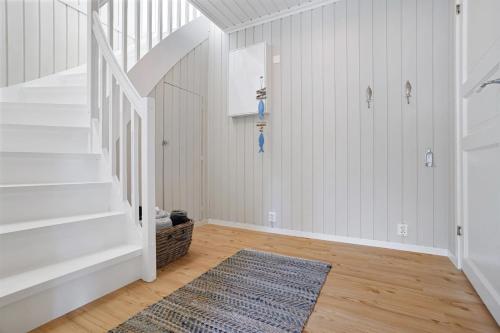 a hallway with white walls and a staircase with a rug at Fjordlykke in Porsgrunn