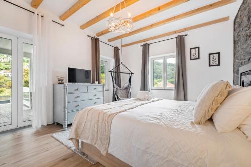 a bedroom with a bed and a tv and windows at Villa Pomar, By OP in Senhora do Rosário