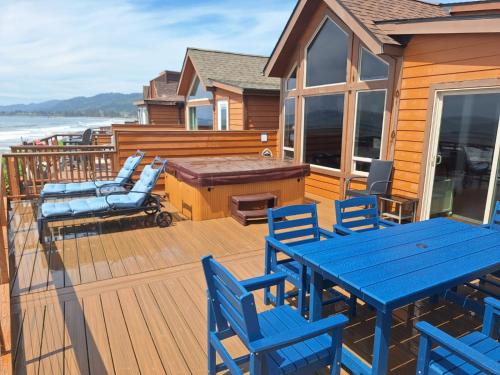 a deck with blue tables and chairs on a house at Ocean Front Cabin 15, Jacuzzi & Sensational Views in Smith River