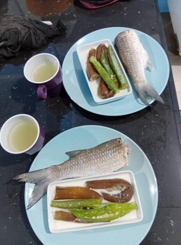 two plates of food with fish and vegetables on a table at Save's Homestay in Nadi
