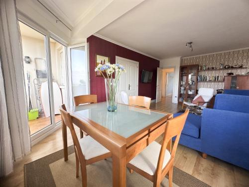 a dining room with a table with a vase of flowers at Apartamento en la playa de Mogro con parking privado in Mogro
