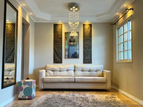 a living room with a white couch and a chandelier at Pavilhão Egípcio in Curitiba