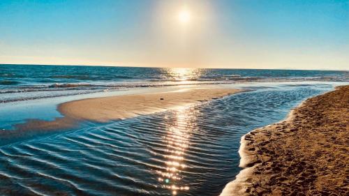 a beach with the sun shining on the water at Bilocale Alborense in Alberese