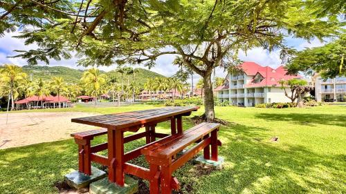 a wooden picnic table sitting under a tree in a park at Grenade 21 vue mer proche plage dans Complexe type Village Vacances in Sainte-Luce
