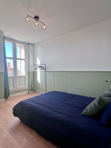 - une chambre avec un lit bleu dans une pièce dotée de fenêtres dans l'établissement Appart' Victoire et Etoile, à Béziers