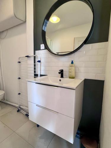 une salle de bain avec un lavabo blanc et un miroir dans l'établissement Appart' Victoire et Etoile, à Béziers