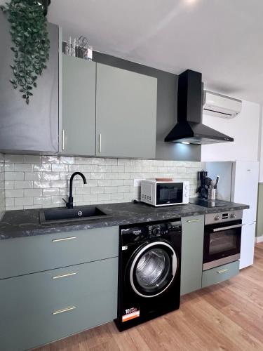 une cuisine avec un lave-linge et un micro-ondes dans l'établissement Appart' Victoire et Etoile, à Béziers