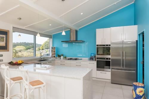 a kitchen with white cabinets and blue walls at Valhalla North & Northern Lodge - waterfront, rural, semi-isolated in Kerikeri