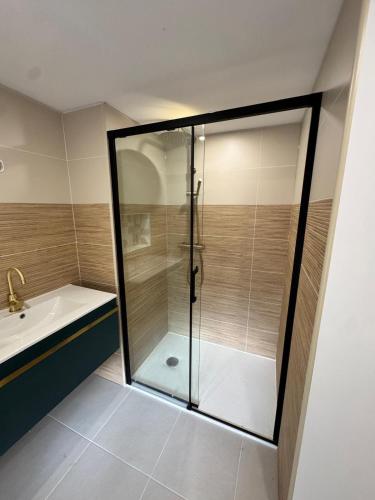 La salle de bains est pourvue d'une baignoire et d'une douche en verre. dans l'établissement Le cottage des remparts Le triplex, à Boulogne-sur-Mer