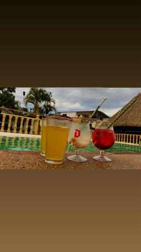 three drinks sitting on a table near a pool at cabañas campestres buena vista in Paicol