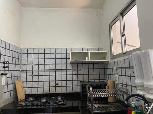 a white tiled kitchen with a stove and a window at COP 30 - Imóvel Próximo ao Aeroporto e ao Hangar - 02 in Belém