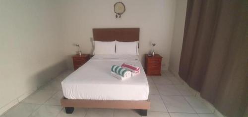 a bedroom with a white bed with two night stands and a clock at HospedajesPerú in Zorritos