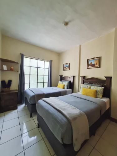 a hotel room with two beds and a window at Mazaryk Bed and Breakfast in Antigua Guatemala