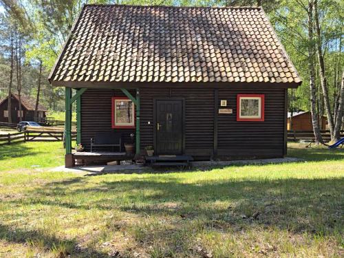 una piccola cabina in un prato di Na Zboczu - Rodzinny Domek w Lesie na Mazurach z Basenem i Sauną a Guzowy Piec