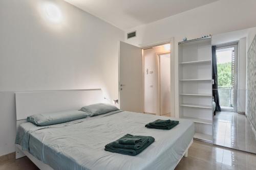 a white bedroom with a bed with two towels on it at Magnolie A47, 6 posti vicino al mare in Eraclea Mare