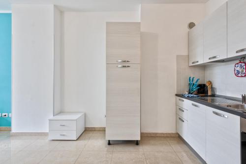 a white kitchen with white cabinets and a sink at Magnolie A47, 6 posti vicino al mare in Eraclea Mare