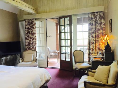 a bedroom with a bed and chairs and a sliding glass door at Le Moulin du Roc in Brantôme