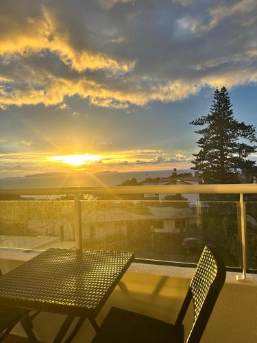 a table and chairs on a balcony with the sunset at Prestige Solmar - Sea View Apartment - Free covered parking - Caniço Center in Caniço