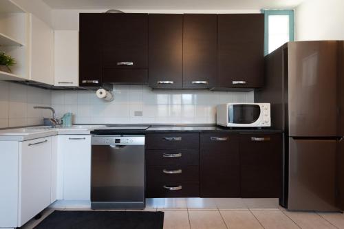 a kitchen with black cabinets and a microwave at Ginestra Deluxe Idromassaggio privato e piscina in Eraclea Mare