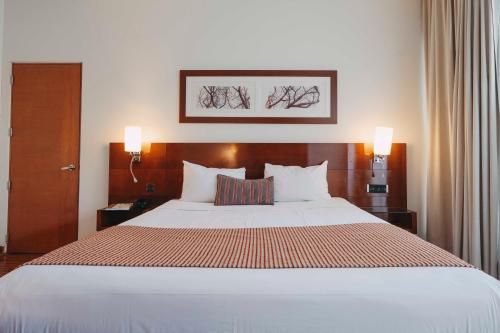 a large bed in a hotel room with two lamps at Time Select - Elegant Apartments in Santiago