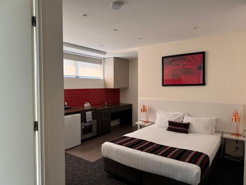 a hotel room with a bed and a kitchen at Comfort Apartments Box Hill in Box Hill