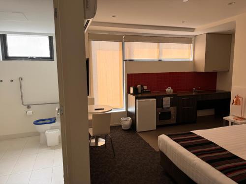 a hotel room with a bed and a bathroom at Comfort Apartments Box Hill in Box Hill