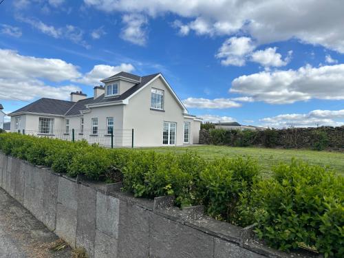 a white house with a retaining wall and bushes at Mullally House Liscannor (Wild Atlantic Way) in Liscannor
