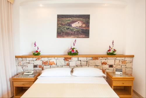 a bedroom with a bed and two tables with flowers at Hotel Terminal - Caroli Hotels in Leuca