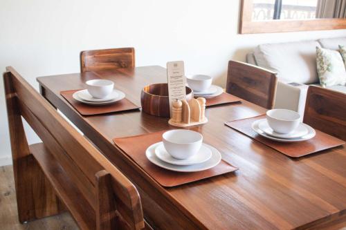 a wooden table with cups and saucers on it at Spacious Apartment with Balcony in El Zonte