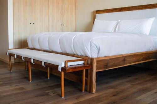 a bed with two pillows on it with a bench under it at Spacious Apartment with Balcony in El Zonte